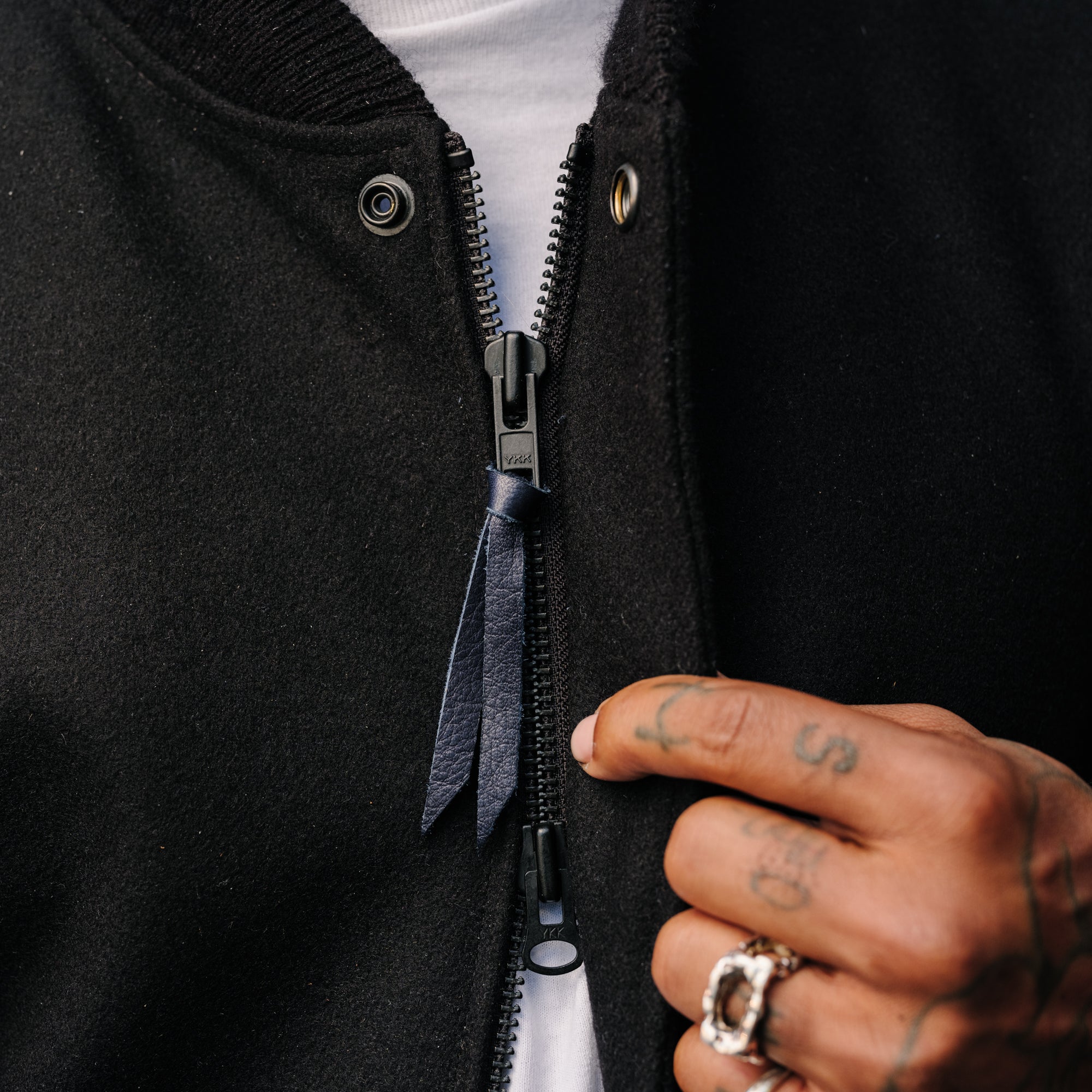 Person wearing a black jacket with a zipper, holding it open.