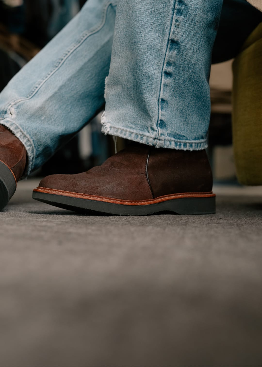 Brown chukka  boots and light blue jeans on a blurred background
