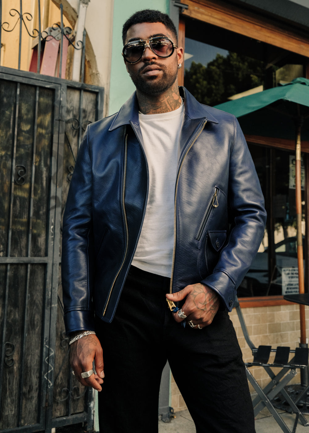 Man wearing a blue leather jacket and sunglasses outdoors