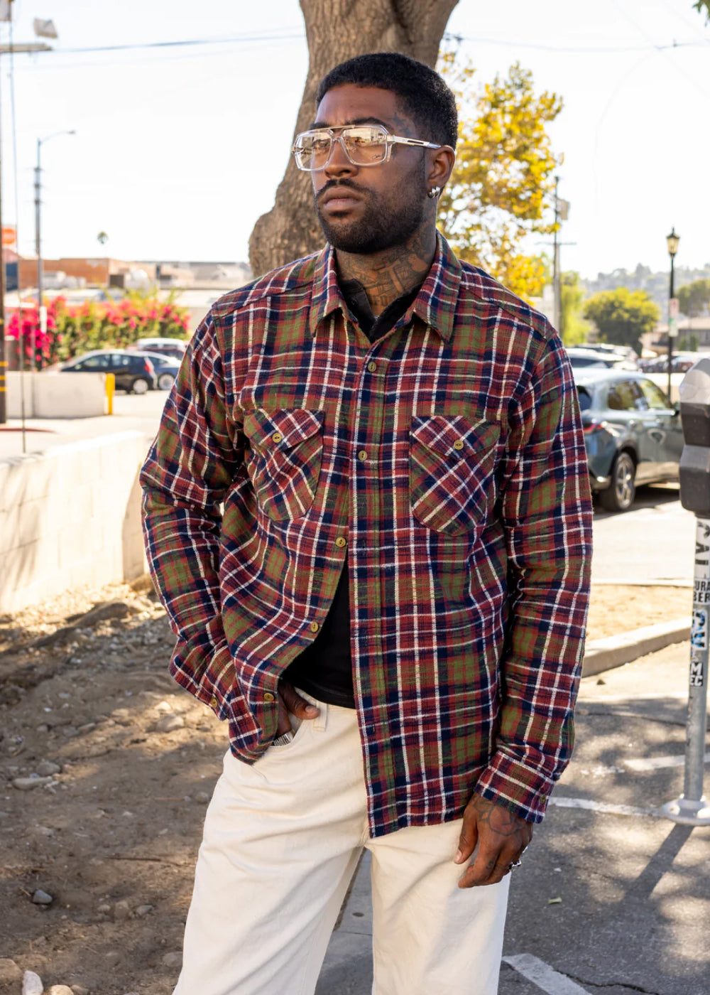 Man wearing a plaid shirt and glasses standing on a street.