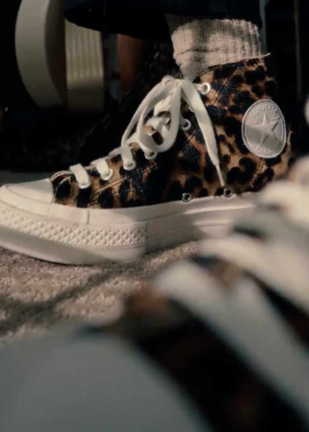 Leopard print high-top sneakers with white laces worn by a person.