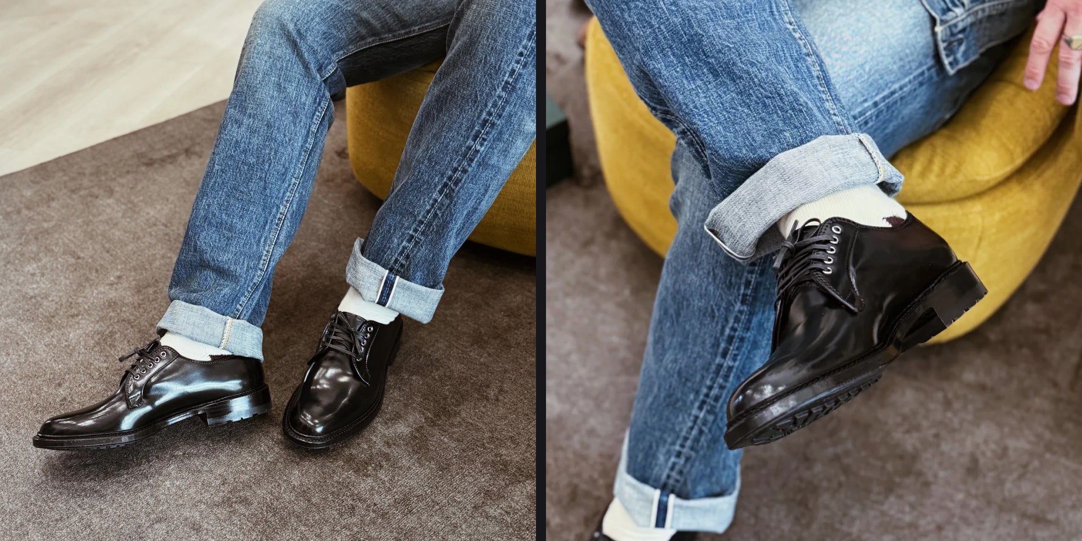Black dress shoes worn with rolled-up blue jeans on a carpeted floor.