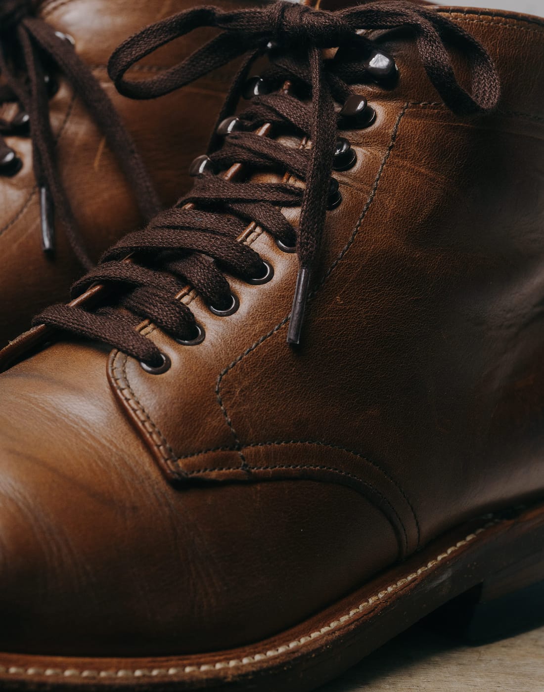 Close-up of brown leather boots with laces on a neutral background