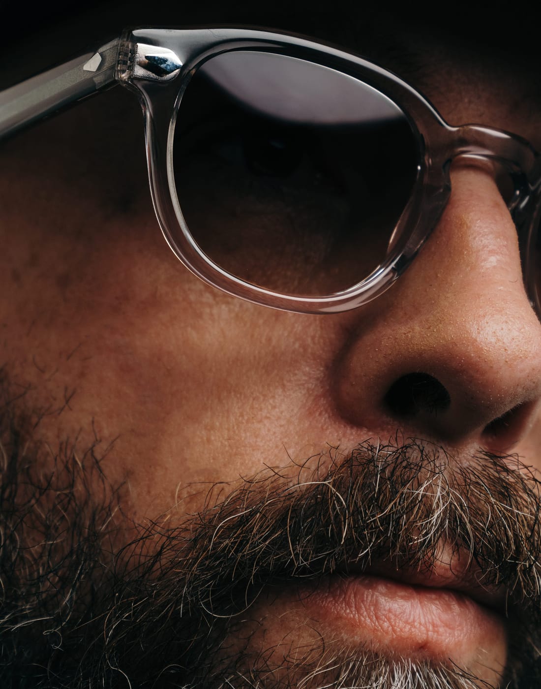 Close-up of a person wearing sunglasses with a dark background