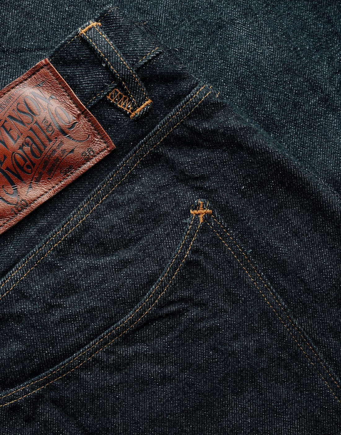 Close-up of dark denim fabric with a leather label